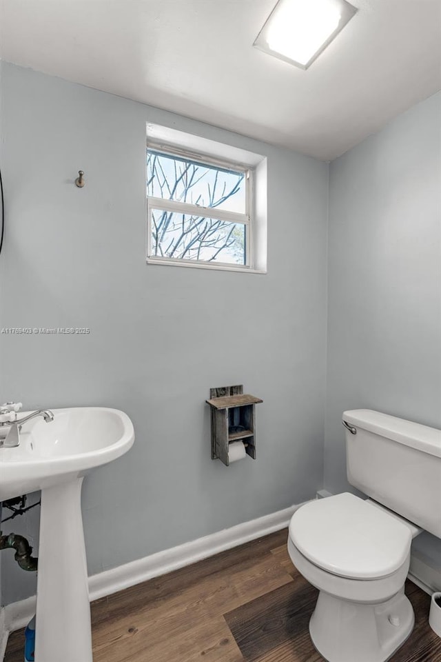 bathroom with toilet, baseboards, and wood finished floors