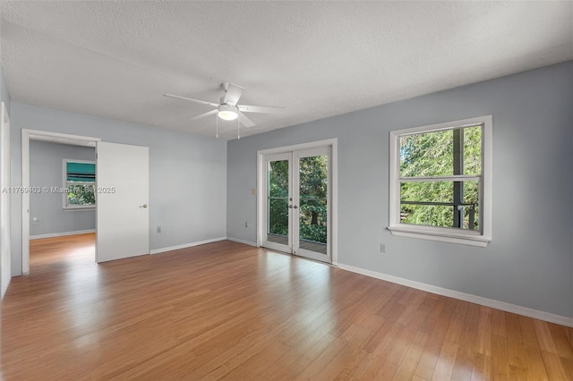 unfurnished room featuring baseboards, a ceiling fan, light wood-type flooring, and plenty of natural light