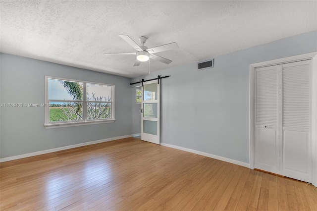 spare room with a ceiling fan, light wood-style flooring, baseboards, and visible vents