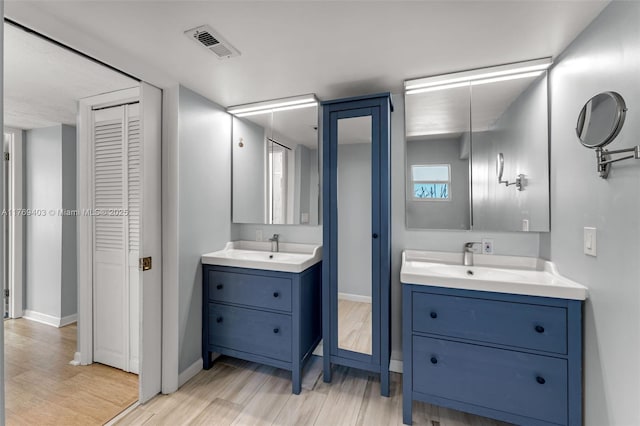 bathroom featuring a sink, two vanities, a closet, and visible vents