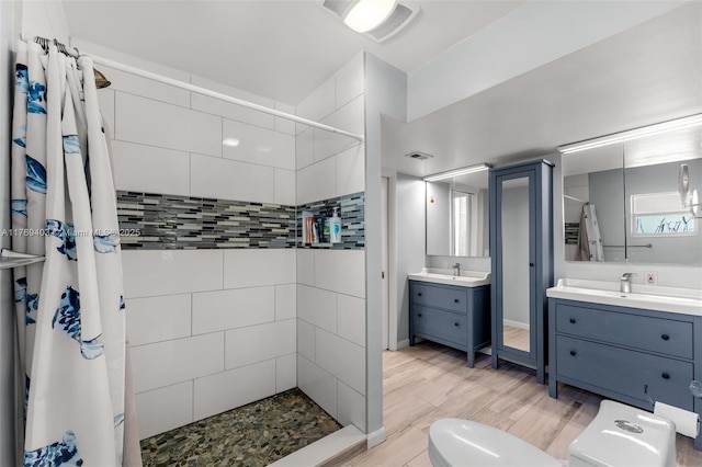 full bath featuring vanity, toilet, a stall shower, visible vents, and wood finished floors