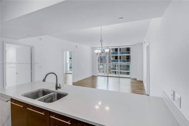 55 SE 6th St Unit 3503, Miami, FL 33131 - kitchen with a sink, light countertops, a chandelier, dark brown cabinetry, and light wood finished floors