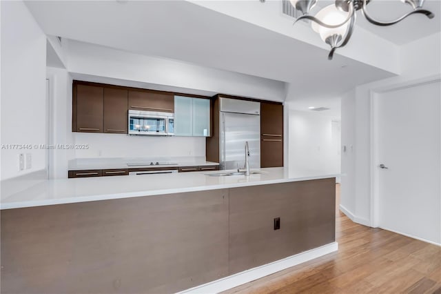 55 SE 6th St Unit 3503, Miami, FL 33131 - kitchen with appliances with stainless steel finishes, a sink, dark brown cabinets, light countertops, and a chandelier