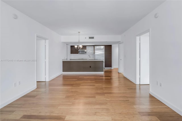 55 SE 6th St Unit 3503, Miami, FL 33131 - unfurnished living room with a chandelier, light wood finished floors, a sink, and baseboards