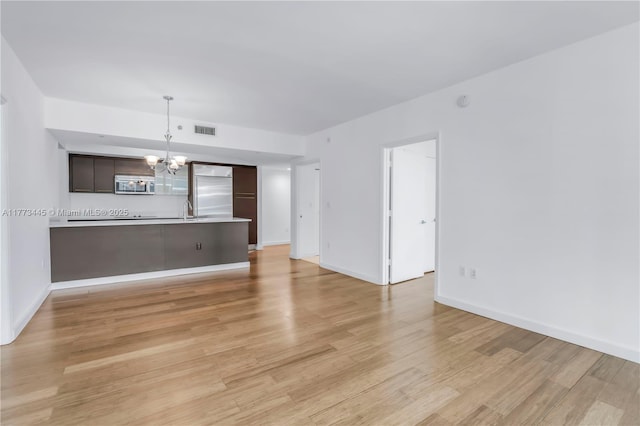55 SE 6th St Unit 3503, Miami, FL 33131 - unfurnished living room featuring a chandelier, light wood finished floors, baseboards, and a sink