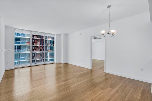 55 SE 6th St Unit 3503, Miami, FL 33131 - empty room featuring a chandelier, light wood finished floors, baseboards, a ceiling fan, and a wall of windows