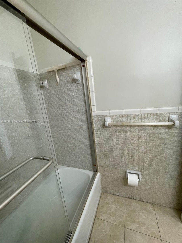 230 SW 11th Ave Unit 15, Hallandale Beach, FL 33009 - bathroom featuring tile walls, tile patterned floors, a wainscoted wall, and bath / shower combo with glass door