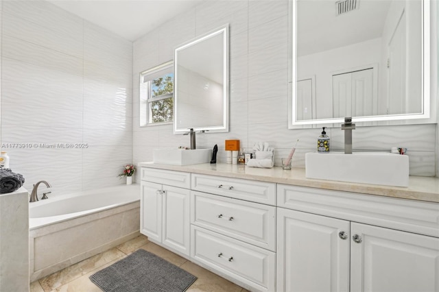 full bathroom with double vanity, visible vents, a bathtub, and a sink