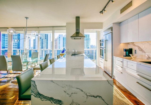 1850 S Ocean Dr Unit 1004, Hallandale Beach, FL 33009 - kitchen with white cabinets, wood finished floors, visible vents, wall chimney range hood, and built in refrigerator