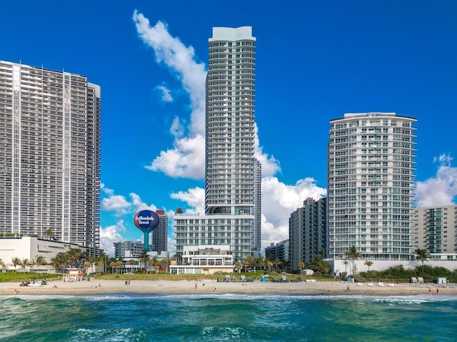 view of swimming pool featuring a water view, a view of city, and a beach view
