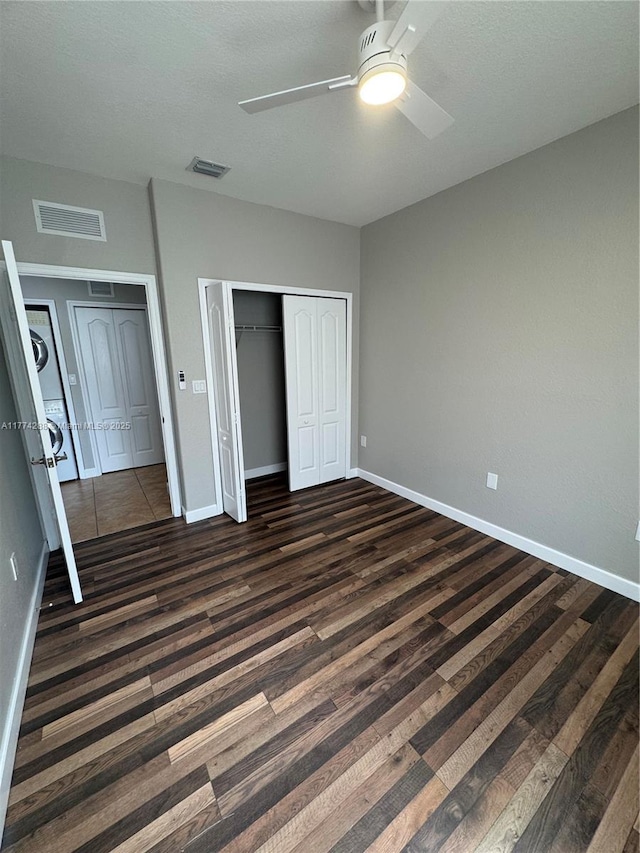 unfurnished bedroom with a closet, dark wood-style floors, and visible vents
