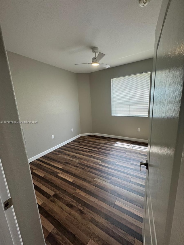 empty room with a ceiling fan, dark wood-style floors, baseboards, and a textured ceiling