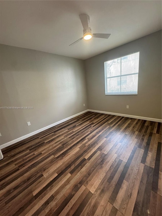 empty room featuring dark wood-type flooring, ceiling fan, and baseboards