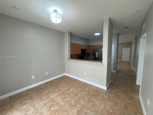 kitchen with black fridge with ice dispenser, visible vents, baseboards, stainless steel microwave, and light tile patterned floors
