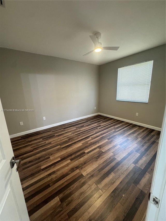 empty room featuring dark wood-style floors, baseboards, and ceiling fan