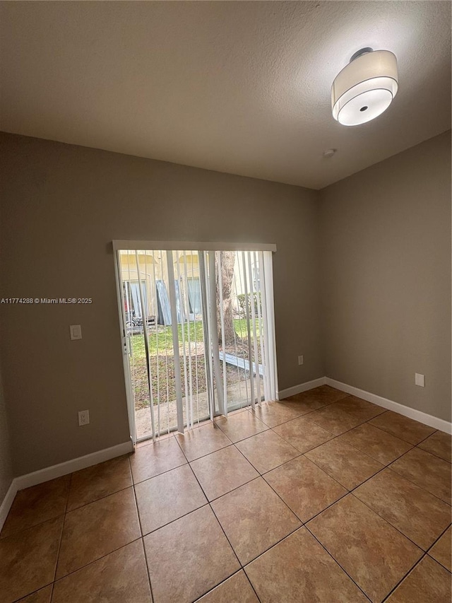 unfurnished room featuring light tile patterned flooring, baseboards, and a textured ceiling