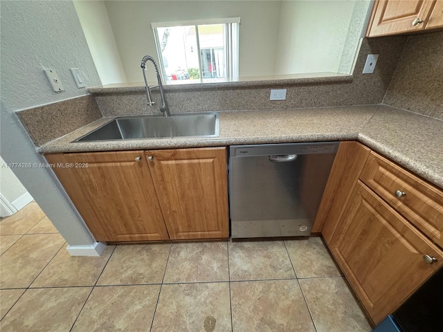 kitchen with dishwasher, a sink, light tile patterned flooring, and brown cabinets