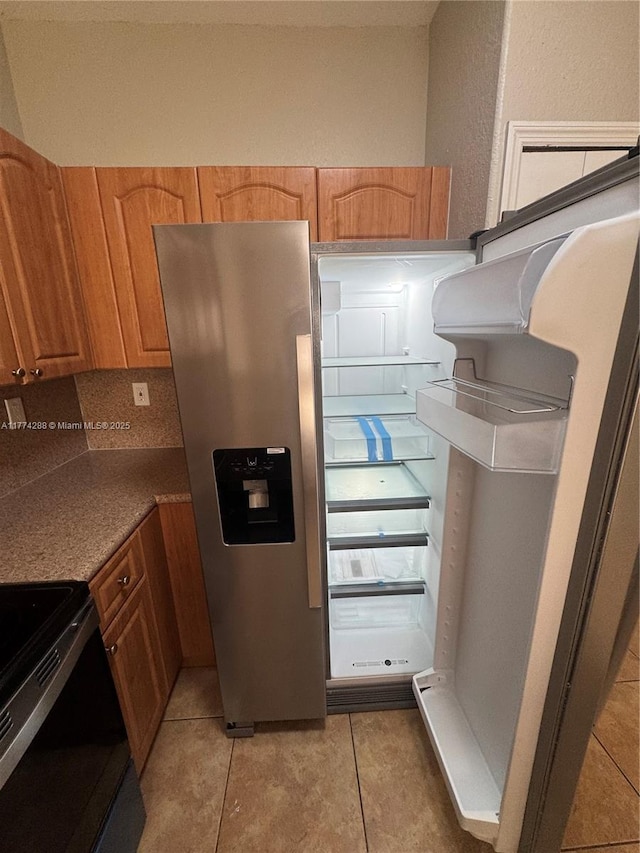 kitchen featuring light tile patterned floors, stainless steel refrigerator with ice dispenser, brown cabinets, and black / electric stove