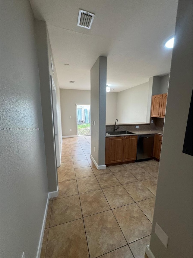 kitchen featuring a sink, dishwasher, light tile patterned floors, baseboards, and visible vents