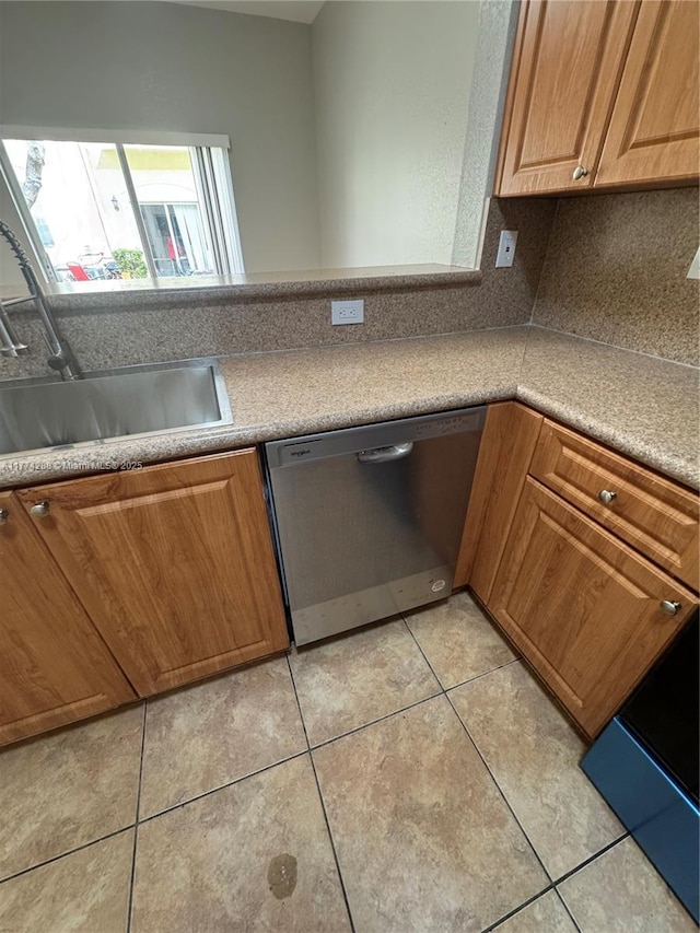 kitchen with light tile patterned flooring, a sink, brown cabinetry, and dishwasher