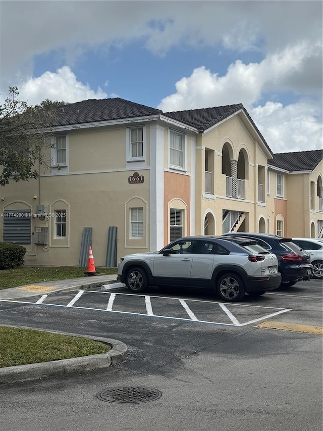 view of front of house featuring a tile roof, stucco siding, and uncovered parking