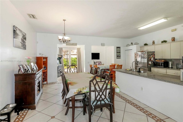 dining area featuring light tile patterned floors, visible vents, and an inviting chandelier