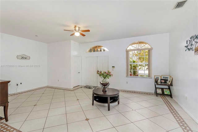 living area featuring light tile patterned floors, visible vents, baseboards, and a ceiling fan