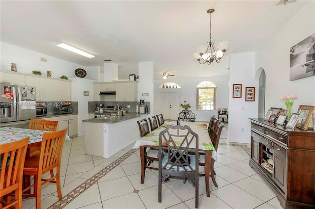 dining space featuring arched walkways, light tile patterned flooring, and ceiling fan with notable chandelier