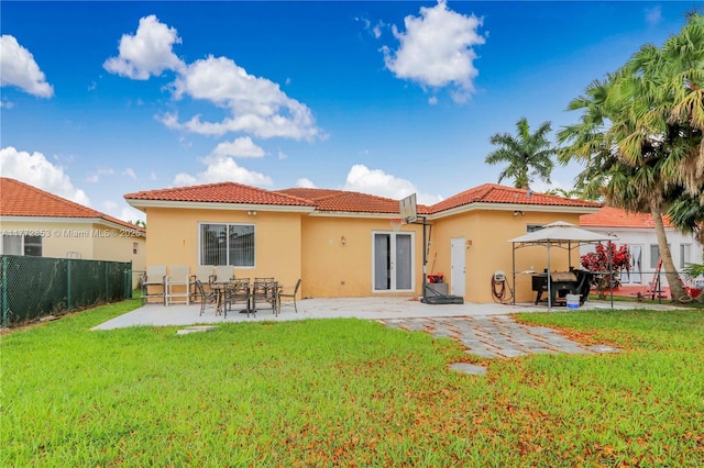 back of property featuring a patio, stucco siding, a fenced backyard, a yard, and a tiled roof