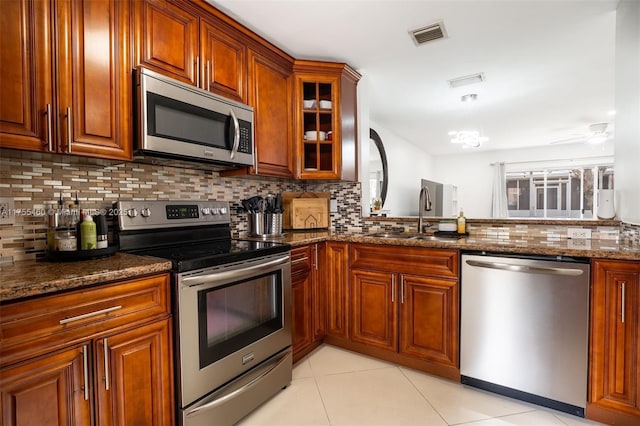 kitchen featuring visible vents, a sink, appliances with stainless steel finishes, decorative backsplash, and light tile patterned flooring