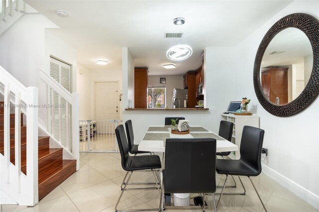 dining area with visible vents, baseboards, light tile patterned floors, and stairs
