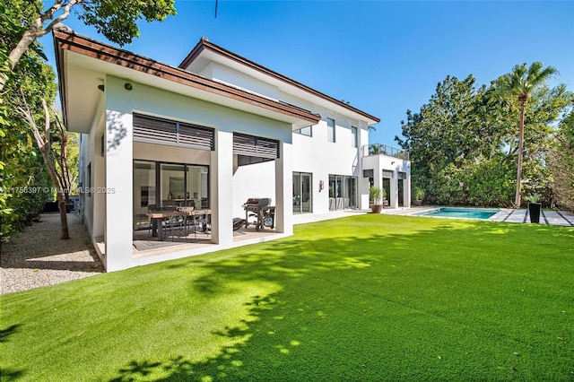 7360 SW 53rd Pl, Miami, FL 33143 - back of house featuring a balcony, an outdoor pool, stucco siding, a lawn, and a patio area