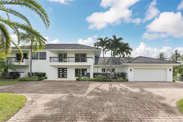 413 Santurce Ave, Coral Gables, FL 33143 - view of front of home with a garage, a balcony, french doors, stucco siding, and driveway