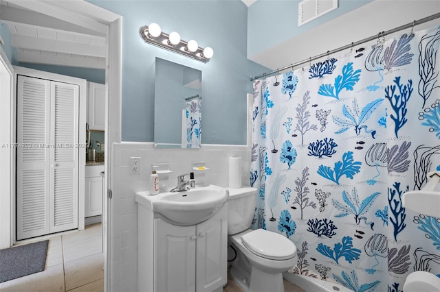 full bathroom with vanity, tile walls, toilet, visible vents, and wainscoting