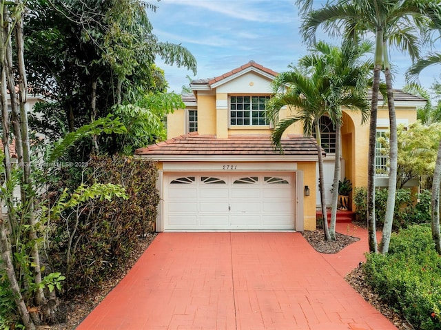 mediterranean / spanish house with stucco siding, driveway, a tile roof, and an attached garage
