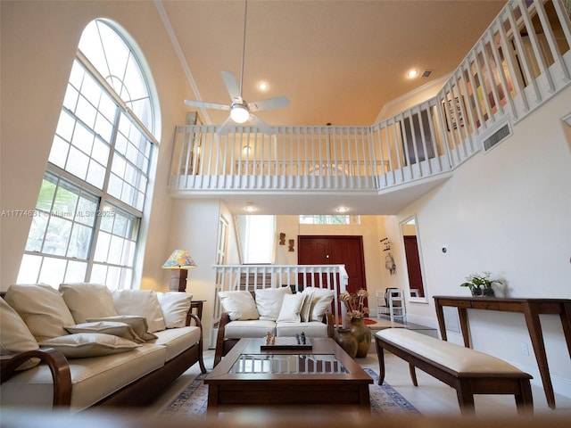 living room with visible vents, a high ceiling, and ceiling fan