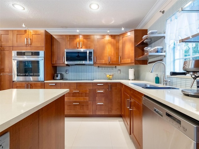 kitchen featuring light countertops, a sink, appliances with stainless steel finishes, and brown cabinetry