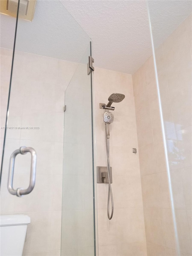 bathroom featuring a shower stall, toilet, and a textured ceiling