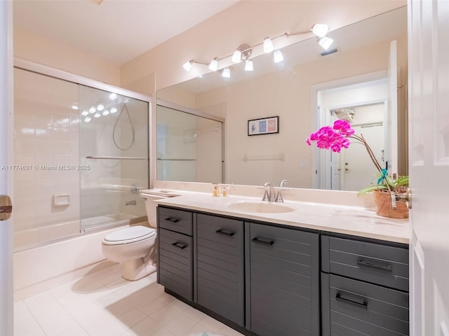 bathroom featuring tile patterned floors, bath / shower combo with glass door, toilet, and vanity