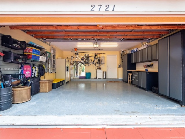 garage featuring a garage door opener and white refrigerator with ice dispenser