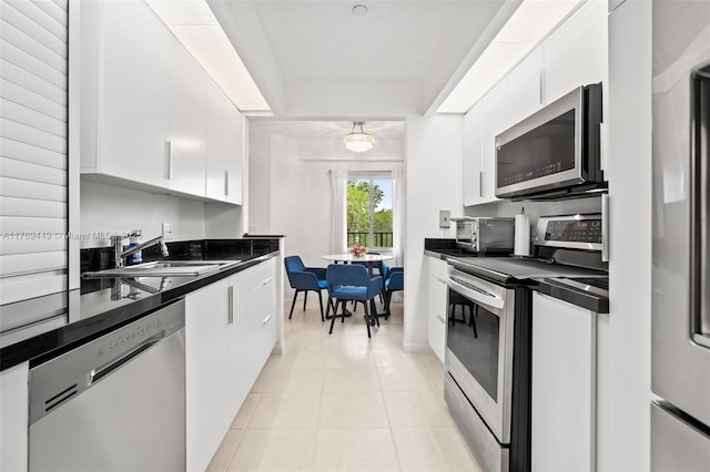 901 SW 141st Ave Unit 409M, Pembroke Pines, FL 33027 - kitchen featuring stainless steel appliances, dark countertops, a sink, white cabinetry, and light tile patterned floors