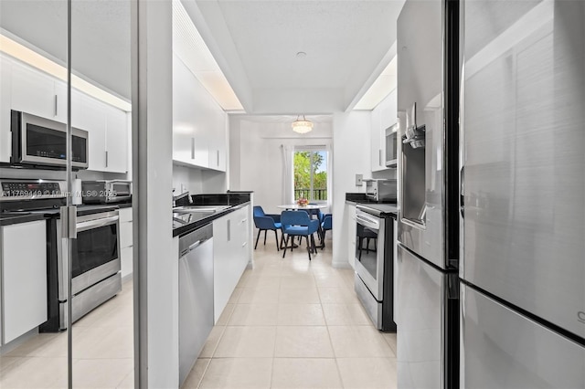 901 SW 141st Ave Unit 409M, Pembroke Pines, FL 33027 - kitchen with appliances with stainless steel finishes, dark countertops, white cabinets, and light tile patterned floors