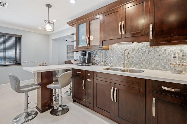kitchen with a sink, ornamental molding, light countertops, and decorative backsplash