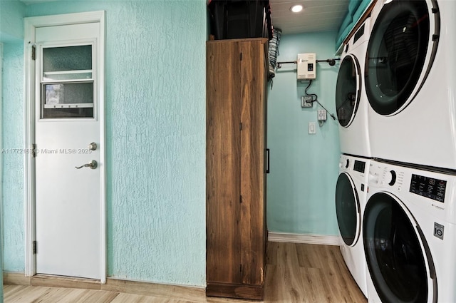 laundry area with light wood finished floors, baseboards, laundry area, and stacked washer and clothes dryer