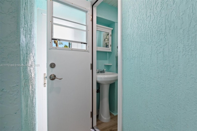 bathroom featuring a textured wall and a sink