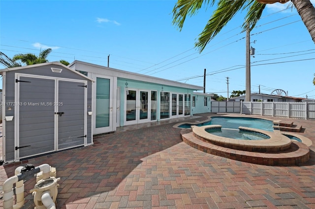 view of swimming pool featuring a storage shed, a fenced backyard, a patio area, an in ground hot tub, and french doors
