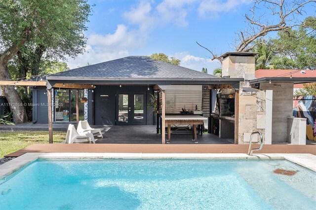 266 NE 117th St, Miami, FL 33161 - rear view of property with an outdoor pool, french doors, and roof with shingles