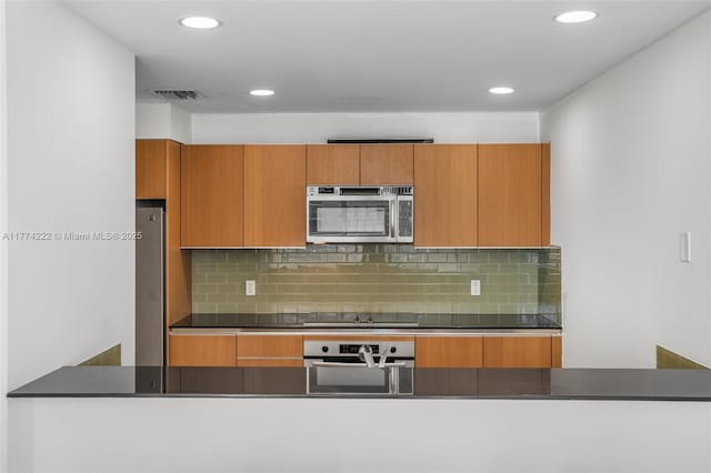 kitchen with dark countertops, stainless steel appliances, tasteful backsplash, and visible vents