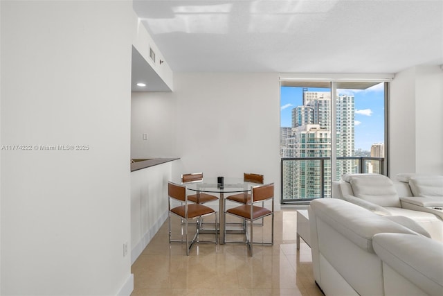 dining room with a city view, expansive windows, baseboards, and light tile patterned floors