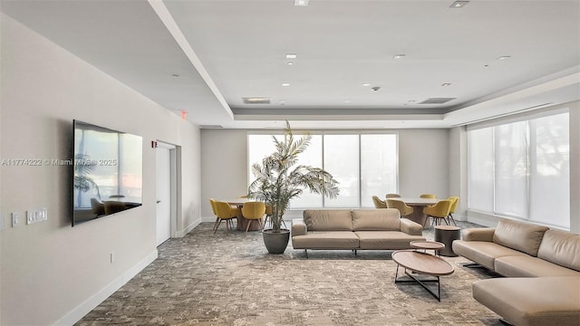 living room featuring a raised ceiling, baseboards, and visible vents